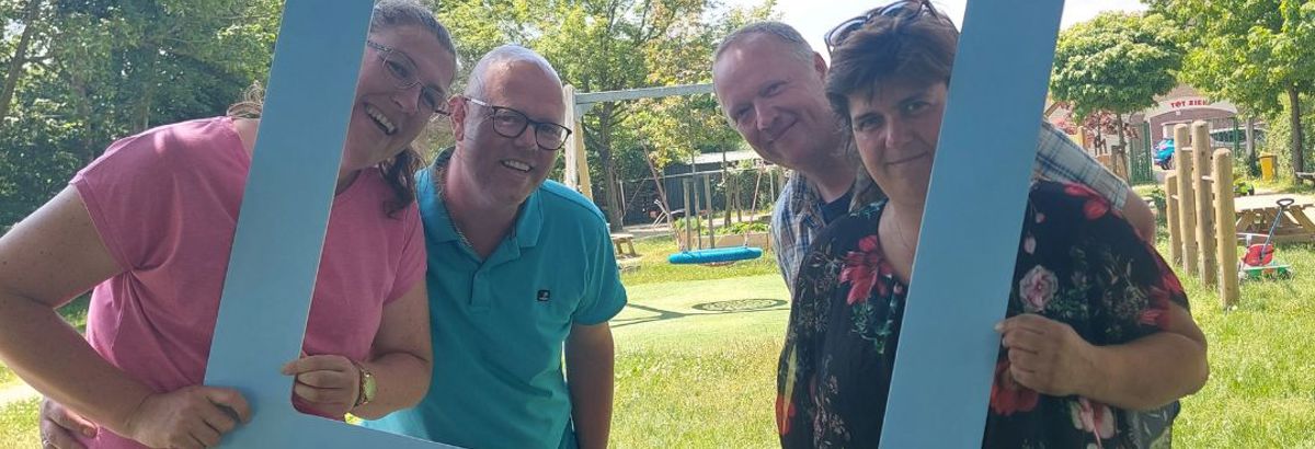 Het team van Jeugdwerk poseert met een bord van 'De grote mensen campagne'
