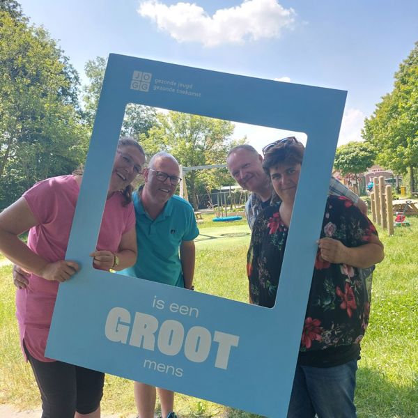 Het team van Jeugdwerk poseert met een bord van 'De grote mensen campagne'