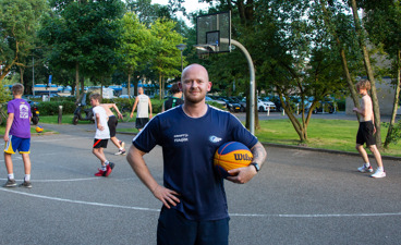 Buurtsportcoach Jochem poseert op het basketbalveld tijdens het 3X3 basketballen