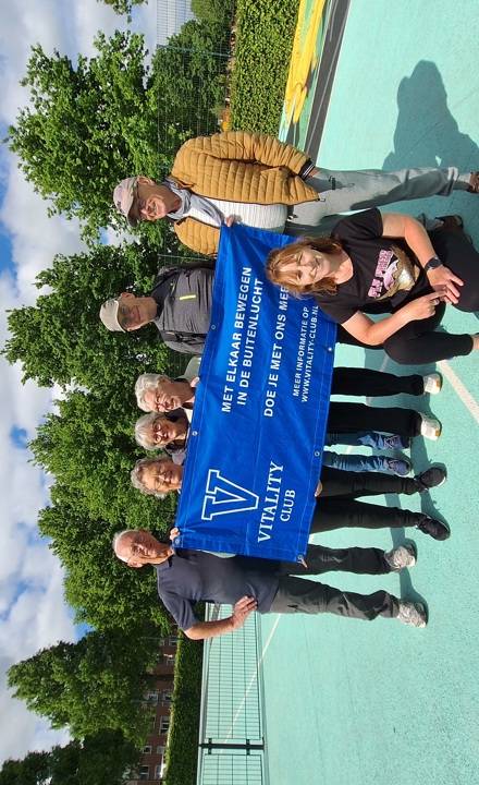 De sporters van de Vitality Club in het Europapark poseren met een reclame banner op het sportveld.