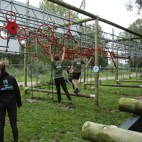 Tieners hangen onder begeleiding van een Fort Alpha instructeur aan een survivalparcours