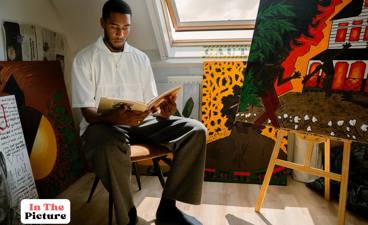 Isodor Slewe poseert tussen zijn schilderijen