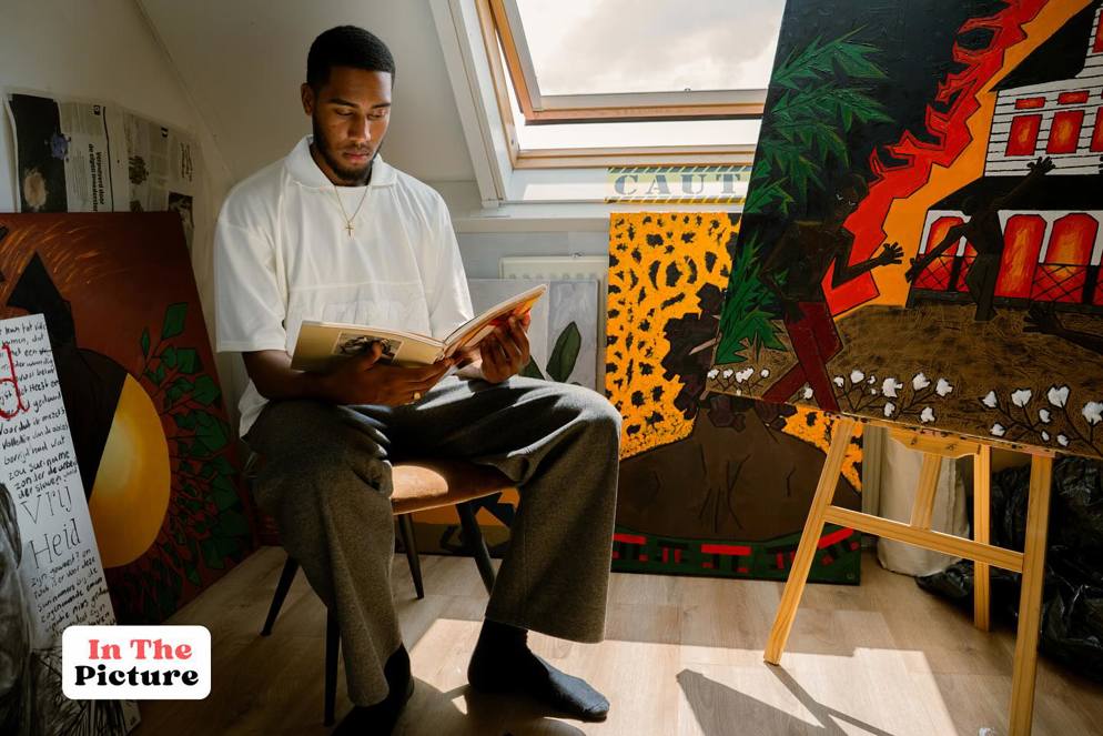 Isodor Slewe poseert tussen zijn schilderijen