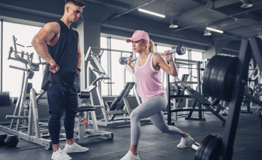 Fitness trainer checkt klant op uitvoering van oefening.