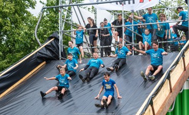 Deelnemers glijden van een grote glijbaan tijdens de Obstacle Run (fotocredit  Rosoriginal)