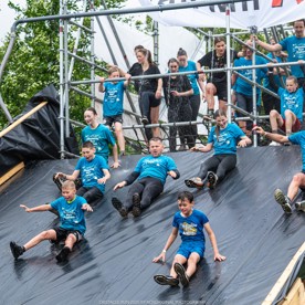 Deelnemers glijden van een grote glijbaan tijdens de Obstacle Run (fotocredit  Rosoriginal)