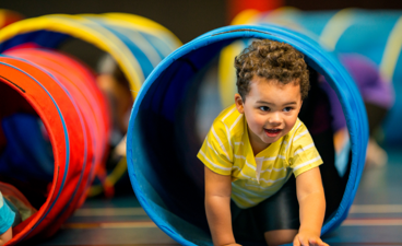 Kindje kruipt door tunnel heen tijdens de gymles.
