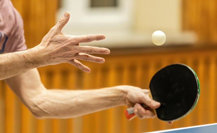 Actiefoto van handen met een tafeltennisbatje en balletje