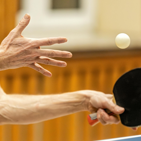 Actiefoto van handen met een tafeltennisbatje en balletje