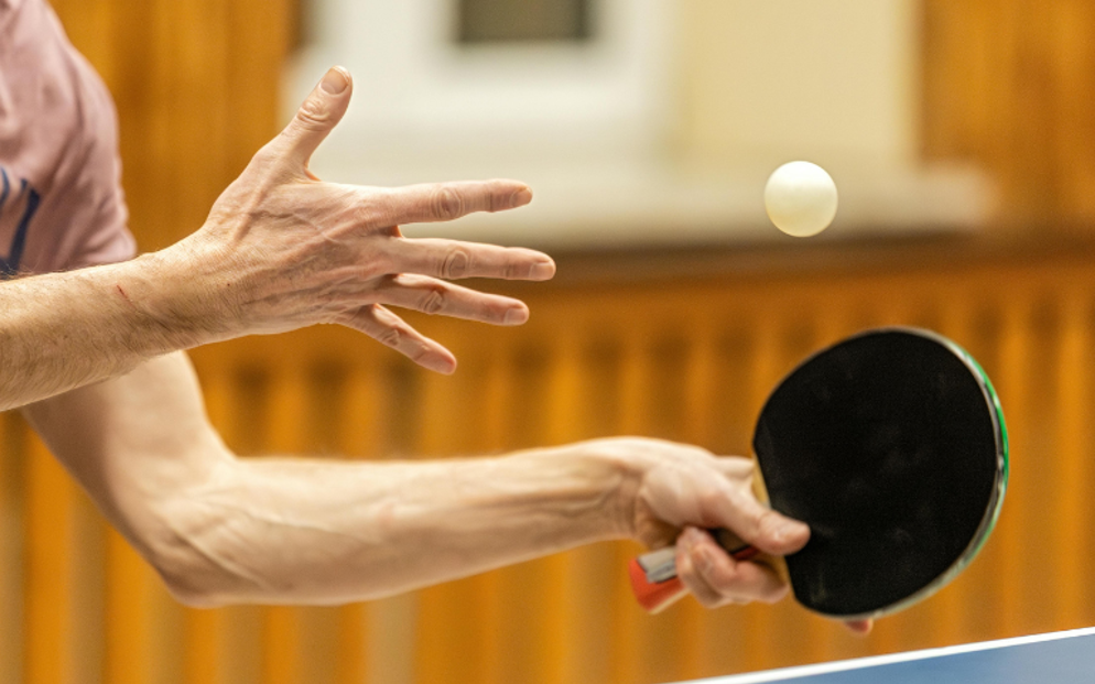 Actiefoto van handen met een tafeltennisbatje en balletje