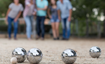 Op voorgrond Petanque ballen, op achtergrond mensen in actie