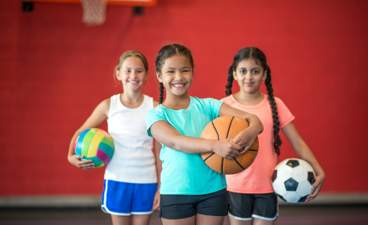 Meiden poseren in sportkleding met verschillende sportmaterialen.