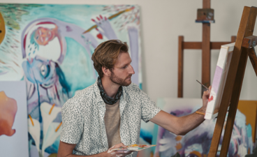 Een man is het aan schilderijen bij een schildersezel