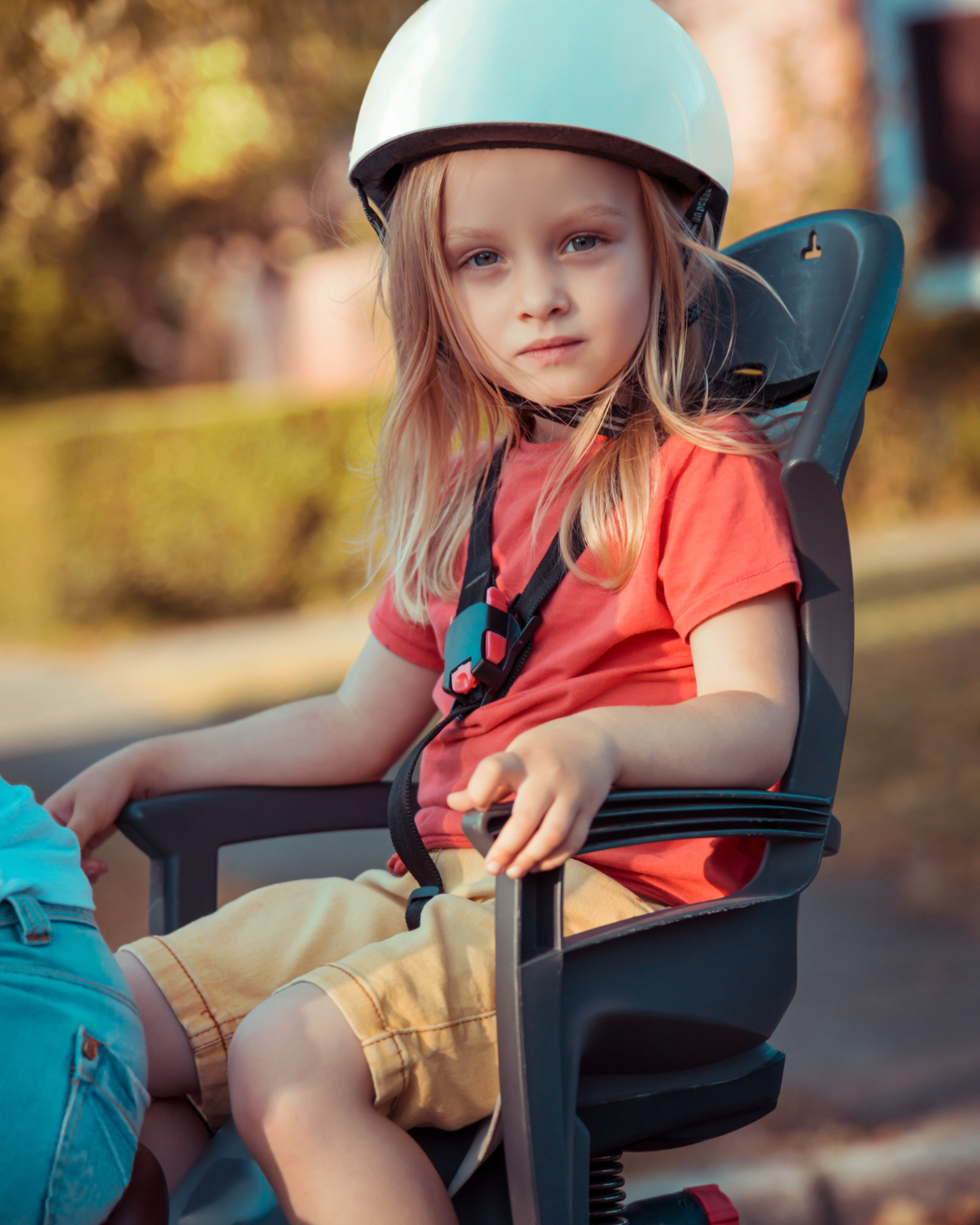 Een klein meisje zit achterop de fiets in een kinderzitje.