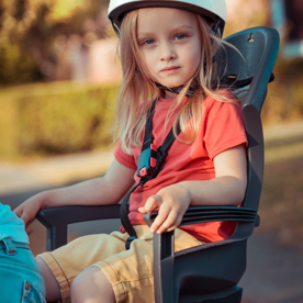 Een klein meisje zit achterop de fiets in een kinderzitje. 