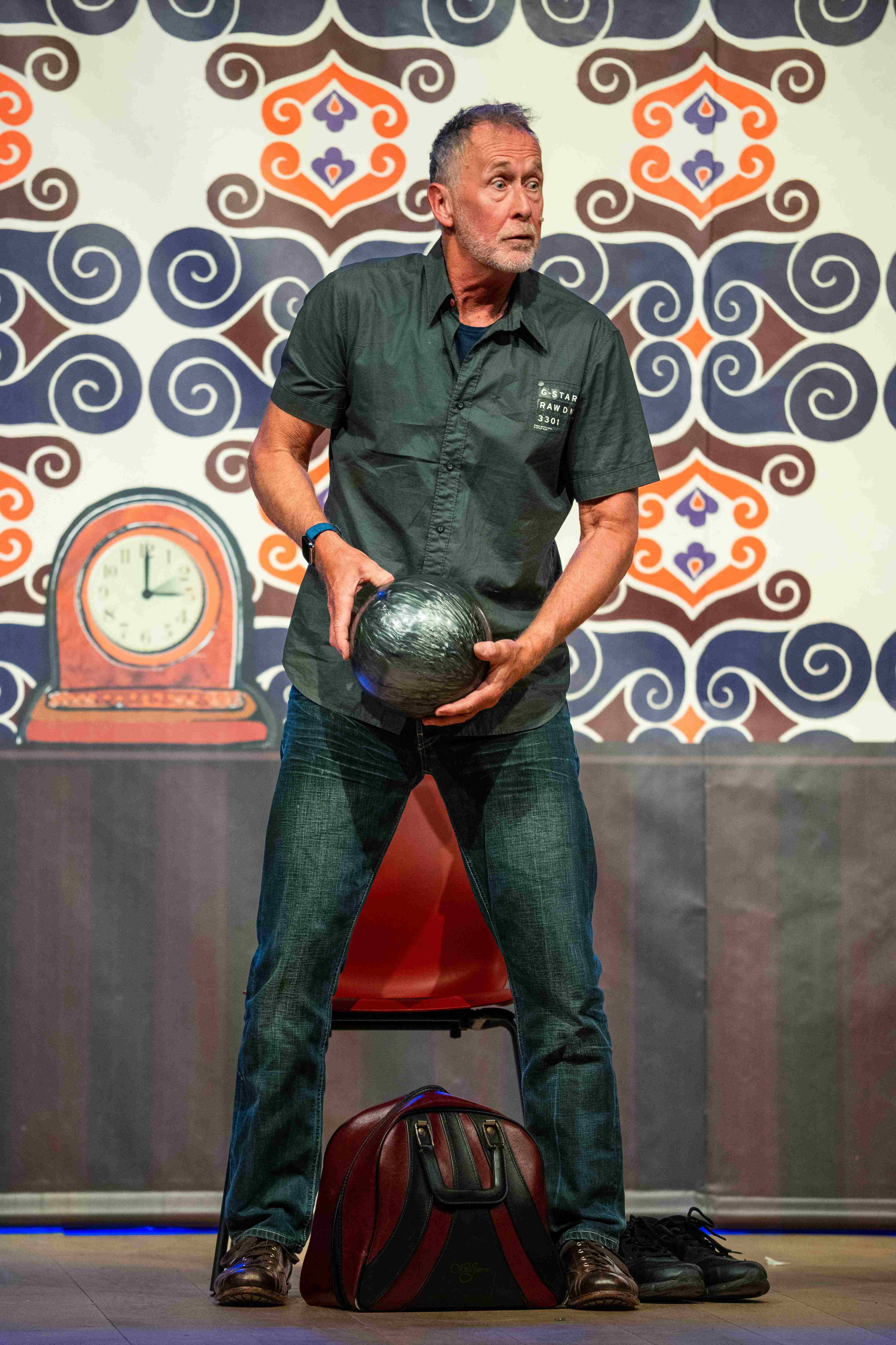 Acteur in toneelvoorstelling staand met bowlingbal