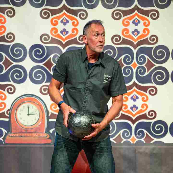 Acteur in toneelvoorstelling staand met bowlingbal