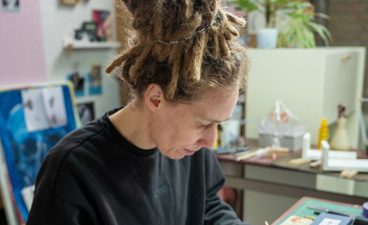 Marjolijn Houdijk zit aan bureau te tekenen