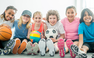 Kinderen zitten naast elkaar met verschillende ballen in de handen. 