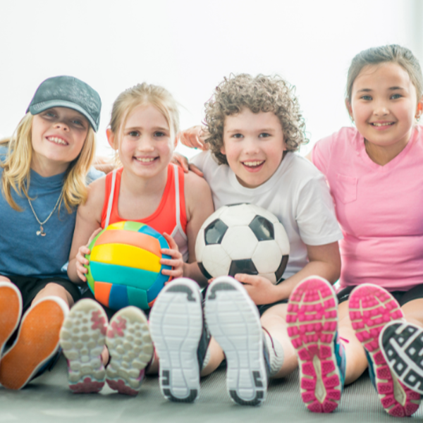 Kinderen zitten naast elkaar met verschillende ballen in de handen. 