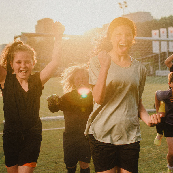 Blije tieners juigen en rennen over een voetbalveld