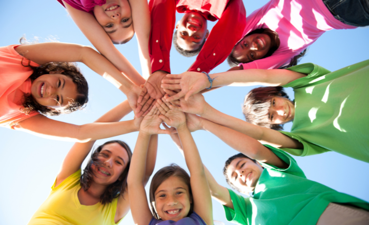 Een groep kinderen hebben allemaal hun handen opelkaar alszijnde high5