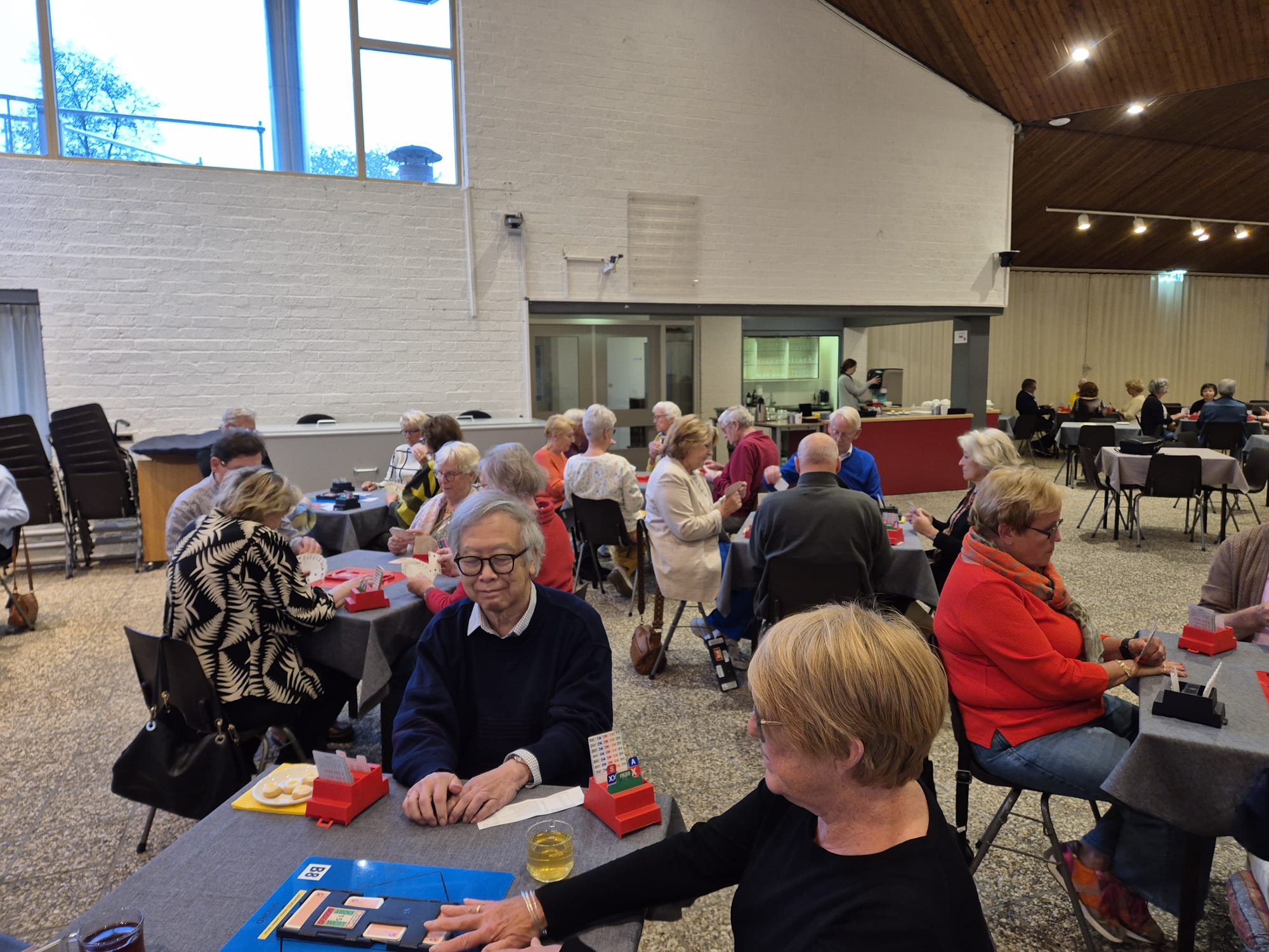 Tientallen clubleden van Bridgeclub Het Groene Hart bridgen tijdens de clubavond.